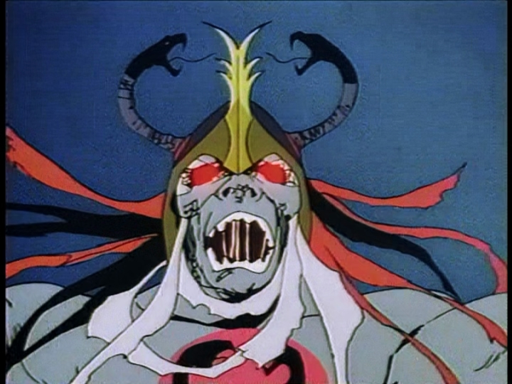A closeup of Mumm-Ra the Ever-Living, his eyes glowing red and his open mouth congested with strings of saliva.